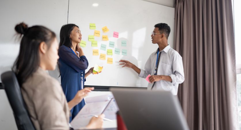 Equipe de marketing frente a um quadro, com post its para desenvolver planejamento anual