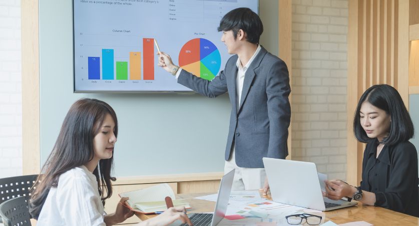 Equipe de 3 especialistas em marketing imobiliário apresentando resultados na tv em uma sala de reunião