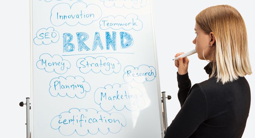 Mulher olhando para quadro em branco escrito com estratégias de branding