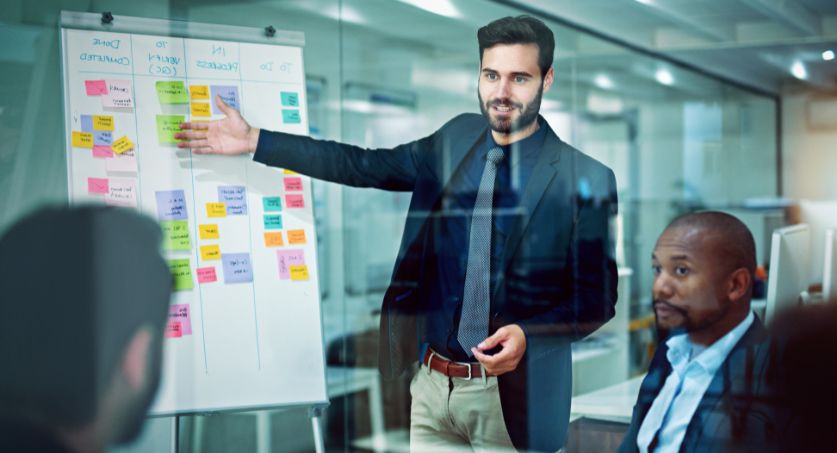 Equipe de 3 pessoas com apresentação de resultados de tráfego pago em um quadro de vidro