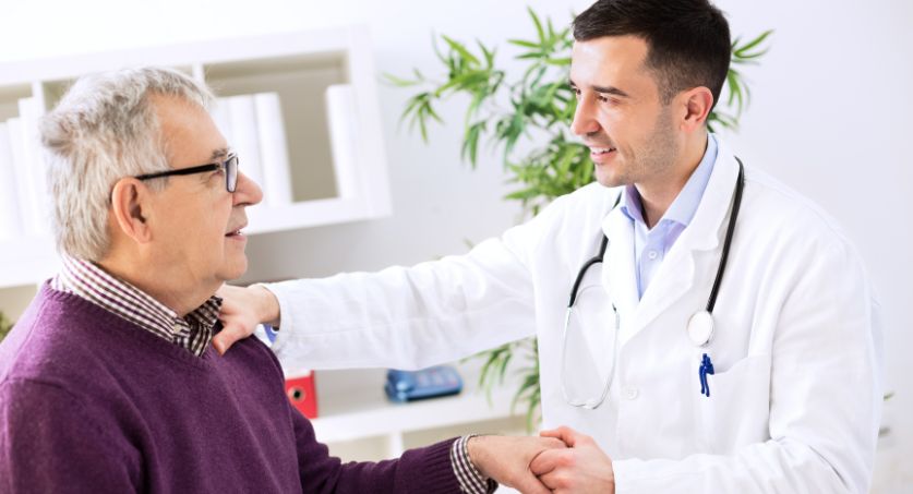 Médico dando as mãos a um paciente de terceira idade e sorrindo, representando a humanização e experiência dos pacientes no marketing médico