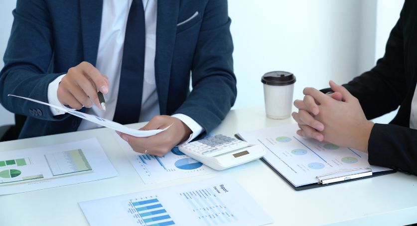 Dois homens em uma mesa de reunião analisando gráficos para planejamento estratégico de tráfego pago