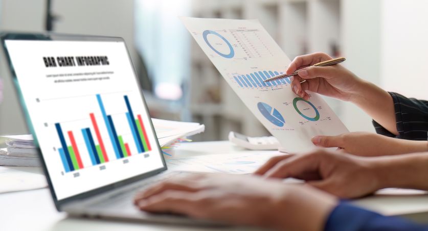 Computador e papel com gráficos de KPIS customer sucess