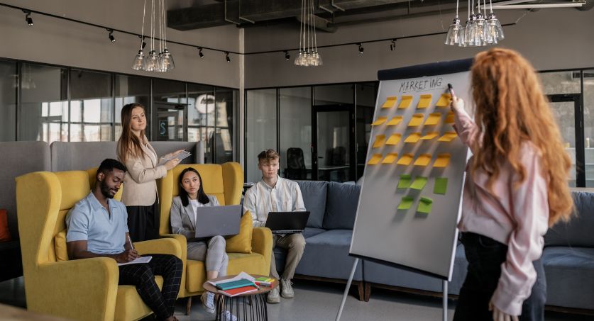 Equipe em reunião planejando ações de marketing e gestão de redes sociais em um quadro com post-its.