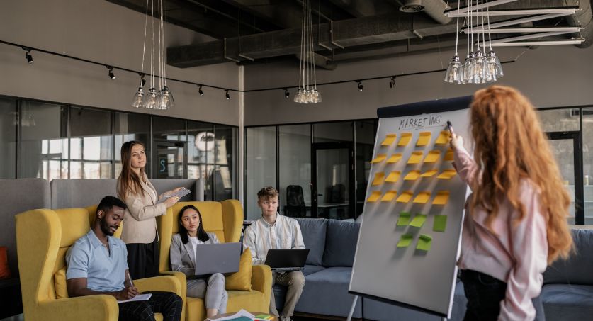 Equipe reunida em escritório durante planejamento de marketing de influência com quadro de ideias e post-its.